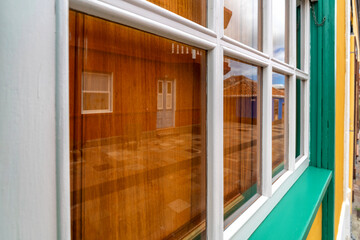 Mediterranes Sprossenfenster aus Holz mit Spiegelung von schönen Häusern in der Altstadt von Los...