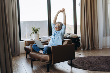 Senior woman stretching while working from home office