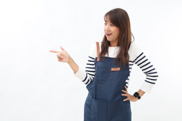 Surprised asian barista pointing finger sideways and amazed, wearing blue apron uniform, standing...