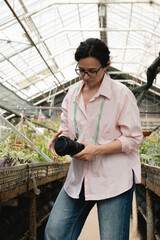 Female reporter photographing agricultural process in greenhouse