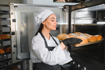 Baker taking freshly baked bread out of oven
