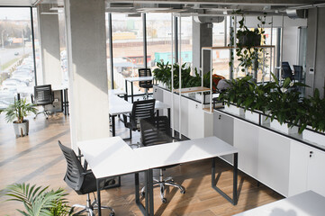 Modern office interior design featuring white desks, black chairs, and green plants