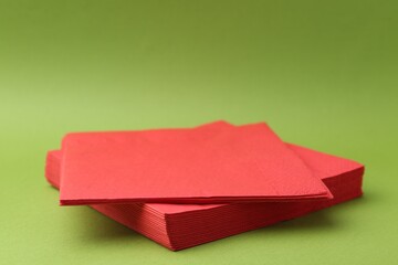 Stack of red handkerchiefs on green background, closeup. Space for text