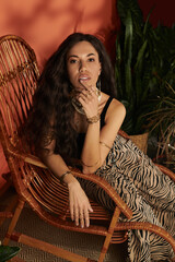 Captivating young woman enjoys summer vibes in a stylish chair surrounded by lush greenery