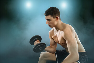 Young Man Working Out in the Gym with Weights. Focused and determined, he lifts during an intense strength training session. Fitness, motivation, and healthy lifestyle