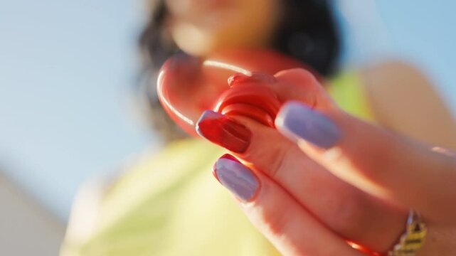 CloseUp View of a Woman Holding Bright Red Objects in a Sunny Outdoor Setting, Captured in a Cheery Mood
