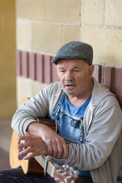 Older man with guitar wearing Yorkshire cap