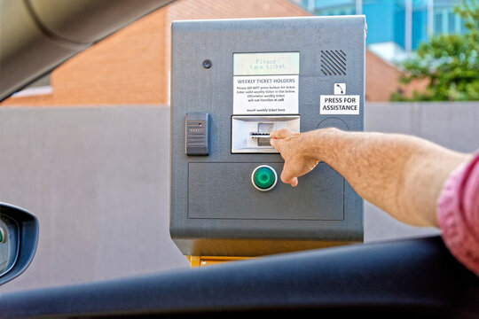 Man taking a ticket from the vending machine for entry to paid undercover parking
