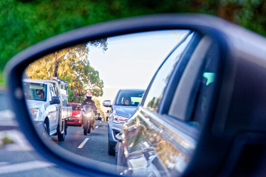 Motorbike rider coming up between cars in peak hour traffic - look out for motorbikes campaign