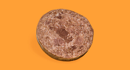 Slice of processed meat on orange background. Close-up image of a round slice of processed isolated meat loaf or canned meat product. Use for food nutrition content, product advertisements