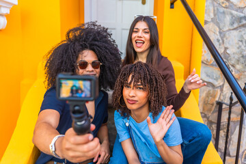 Young content creators filming video on action camera in front of colorful building