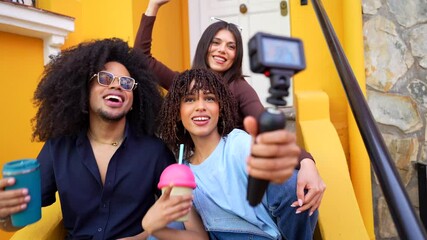 Young content creators filming a promotional video for social media, enjoying beverages on vibrant yellow steps
