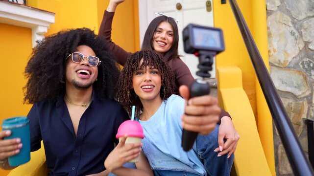 Young content creators filming a promotional video for social media, enjoying beverages on vibrant yellow steps