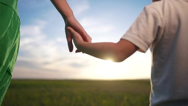 Mom and son join hands in the garden park. Concept of love in family of woman mother to son. Close-up of family hands. Close-up of mother and son joining forces in the park of lifestyle.