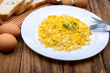 fresh scrambled eggs on white plate on breakfast table
