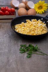 Scrambled eggs in an iron pan on the rustic wooden table