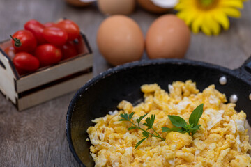 Scrambled eggs in an iron pan on the rustic wooden table