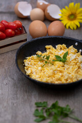 Scrambled eggs in an iron pan on the rustic wooden table