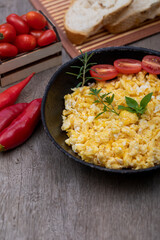 Scrambled eggs in an iron pan on the rustic wooden table