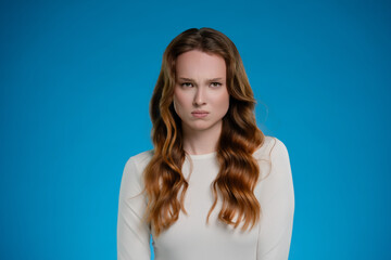 Fototapeta premium Woman expressing strong emotions while posing in a studio with a vibrant blue background