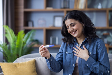 A joyful woman is thrilled to see a positive result on her pregnancy test at home.