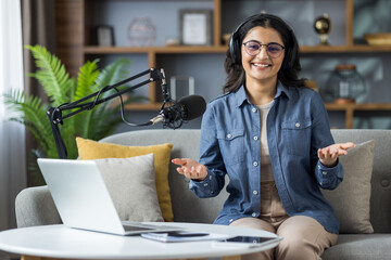 Smiling woman with headphones and glasses gets ready to speak at podcasting studio.