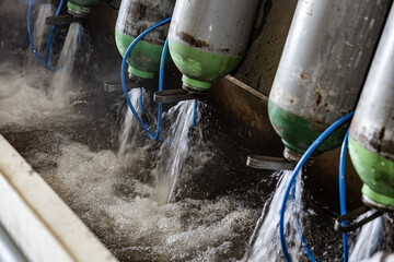 Rusted green and silver gas cylinders expelling water in a testing or maintenance station with...