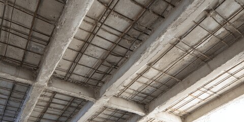 Obraz premium Exposed grid of concrete beams and rusted rebar in an unfinished ceiling 