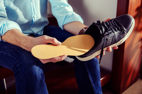 Elegant man holds a leather shoe and puts insole in it