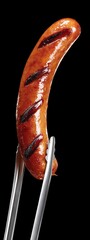 grilled smoked sausage being held with barbecue tongs . aspect ratio 3:8