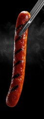 grilled smoked sausage being held with barbecue tongs . aspect ratio 3:8