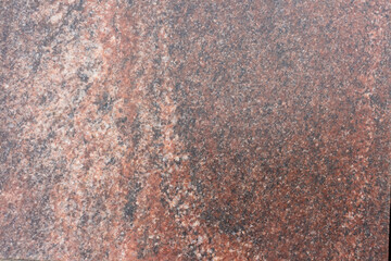 Close-up view of a rugged reddish granite stone surface showcasing unique natural patterns and textures. This stone features a diverse array of mineral inclusions, creating visual interest.