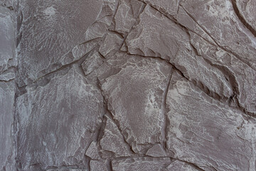 The wall features a detailed surface resembling natural stone with a neutral color palette. The...