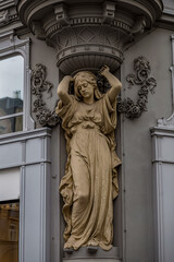 Elegant architectural sculpture of a woman in classical style decorates a historic building facade,...