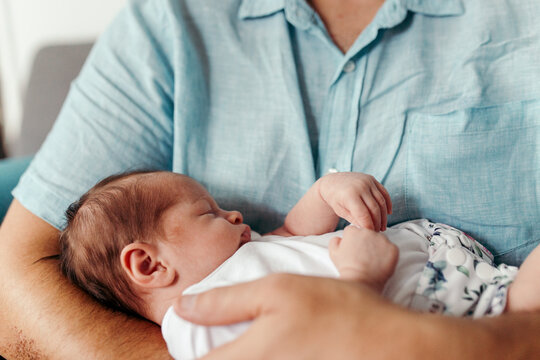 Newborn baby girl sleeping in father's arms