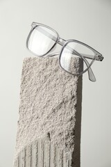 Stylish glasses on stone surface against light grey background, closeup