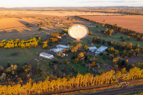 Aerial view of a large satellite dish on rural farmland in late afternoon sunshine