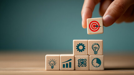 Wooden blocks with icons representing goal achievement, placed on a table, symbolizing strategic planning and business success