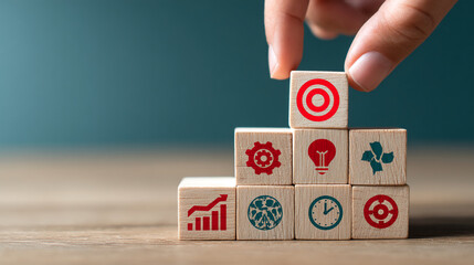 Wooden blocks with icons form a staircase, symbolizing growth, planning, and achieving goals.  A hand places the final block, highlighting strategic steps