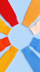 Colorful sweater sleeves arranged in a circle against a soft blue background