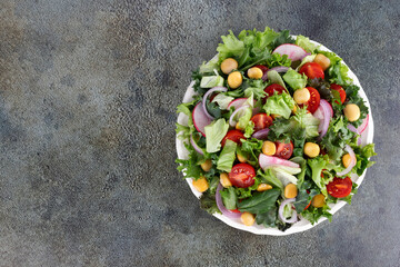 Green salad with cherry tomatoes, red onion and protein-rich lupines beans on green background. Vegetarian food.