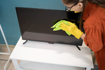 housecleaning concept. Woman wiping tv screen with rag in the living room.