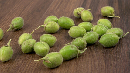 Fresh Green chickpeas on a branch, and in the pod, isolated on wooden background.