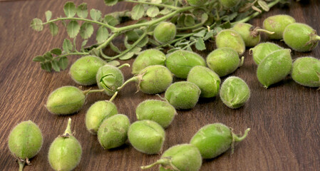 Fresh Green chickpeas on a branch, and in the pod, isolated on wooden background.