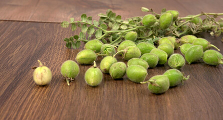 Fresh Green chickpeas on a branch, and in the pod, isolated on wooden background.