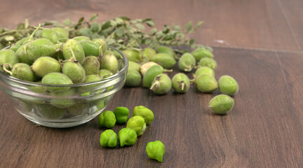 Fresh Green chickpeas on a branch, and in the pod, isolated on wooden background.