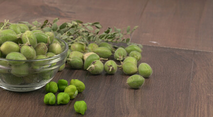 Fresh Green chickpeas on a branch, and in the pod, isolated on wooden background.