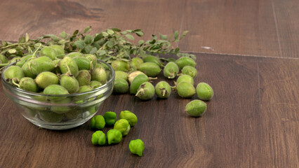 Fresh Green chickpeas on a branch, and in the pod, isolated on wooden background.