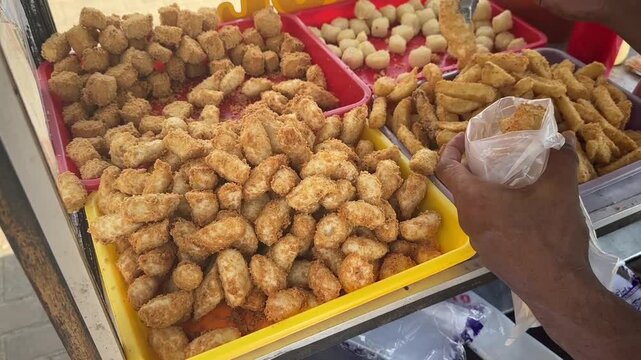 Crispy fried tofu and savory potato otak-otak, popular Indonesian street food snacks, freshly prepared and ready to enjoy at a local food stall. BSD, Indonesia - May 1, 2025