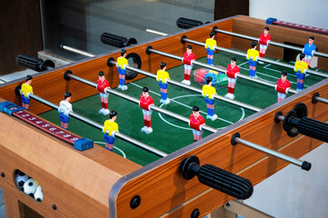 Classic wooden foosball table with colorful player figures arranged in play positions on green...